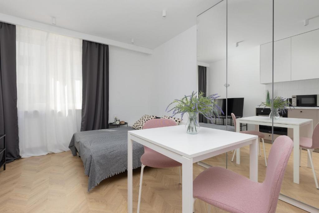 sala de estar con mesa blanca y sillas rosas en Modern & Cozy Apartment Warsaw Downtown by Renters en Varsovia