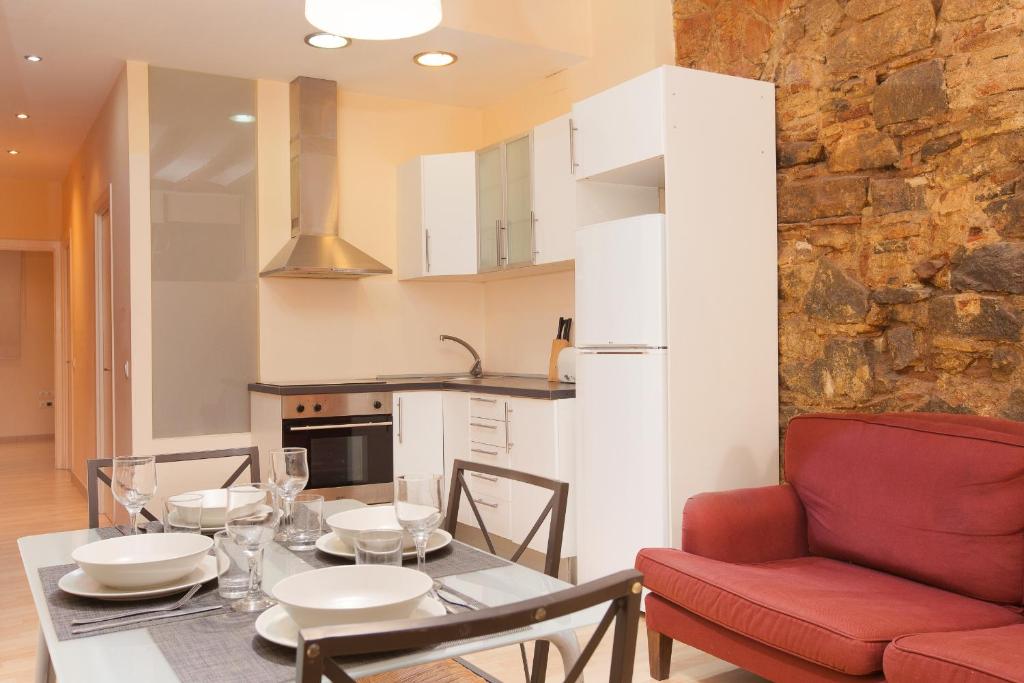 巴塞隆納的住宿－Gothic - Ramblas Apartments，厨房以及带桌子和红椅的用餐室