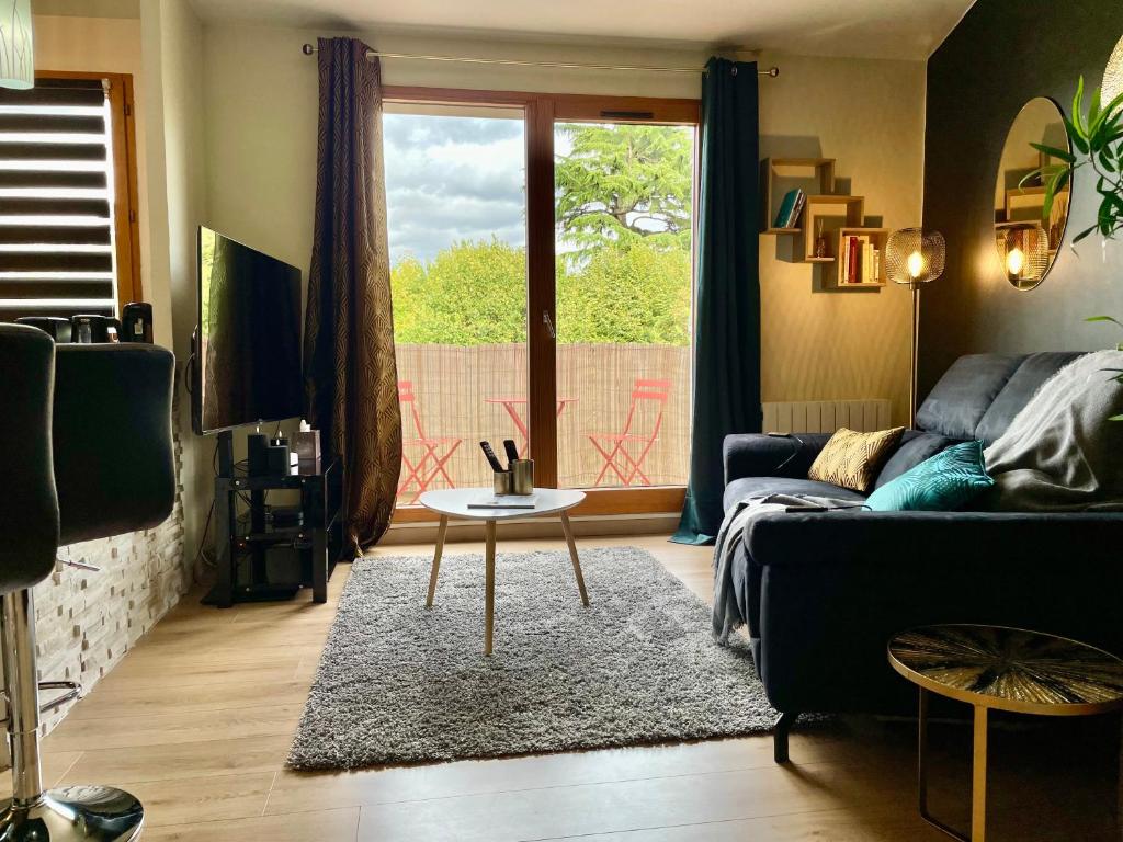 een woonkamer met een bank en een tafel bij Séjour Business & Famille, 2 chambres, Parking & WiFi in Brétigny-sur-Orge