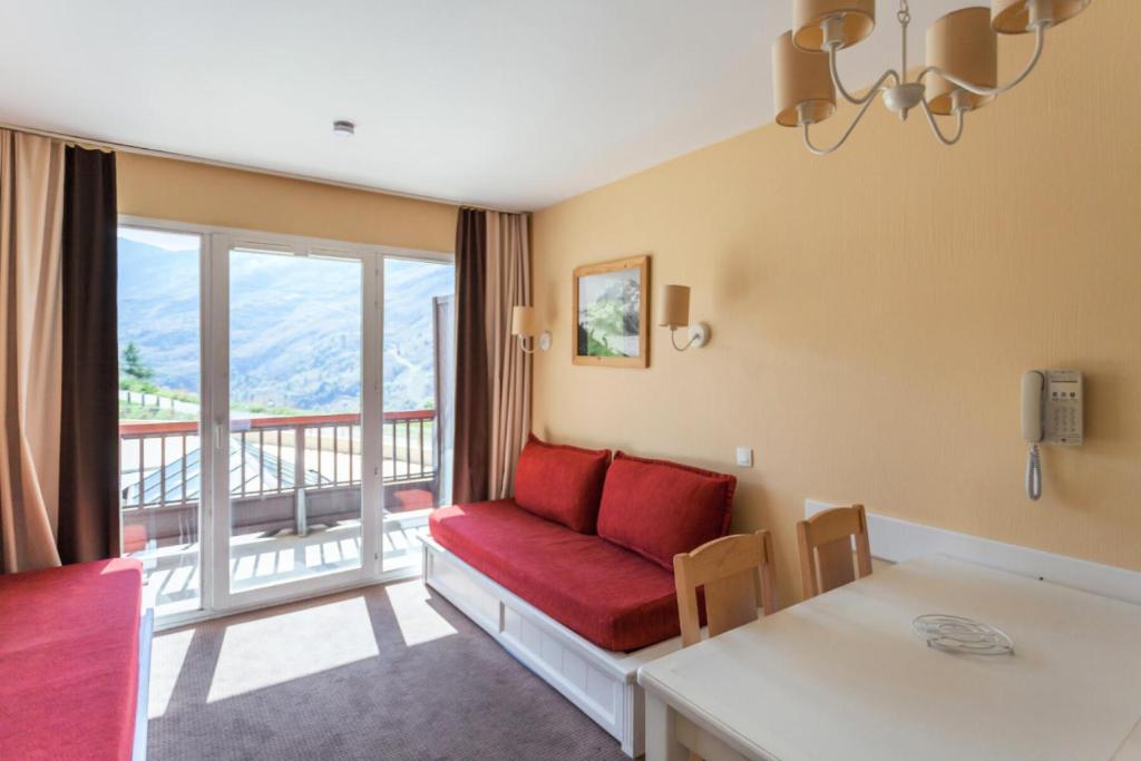 un salon avec un canapé rouge et un balcon dans l'établissement Résidence Le Thabor - maeva Home - 2 Pièces 5 Personnes Confort MAE-7571, à Le Désert