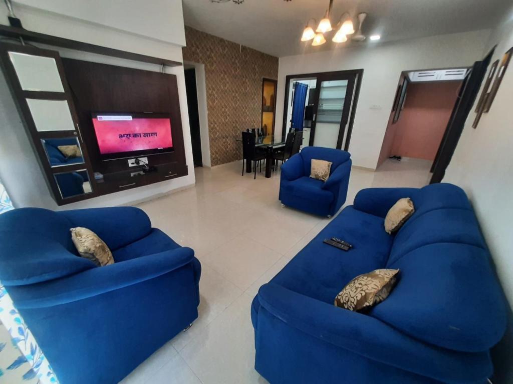 sala de estar con 2 sofás azules y TV en Staeg Skyline View 3BHK - 1404 en Indore