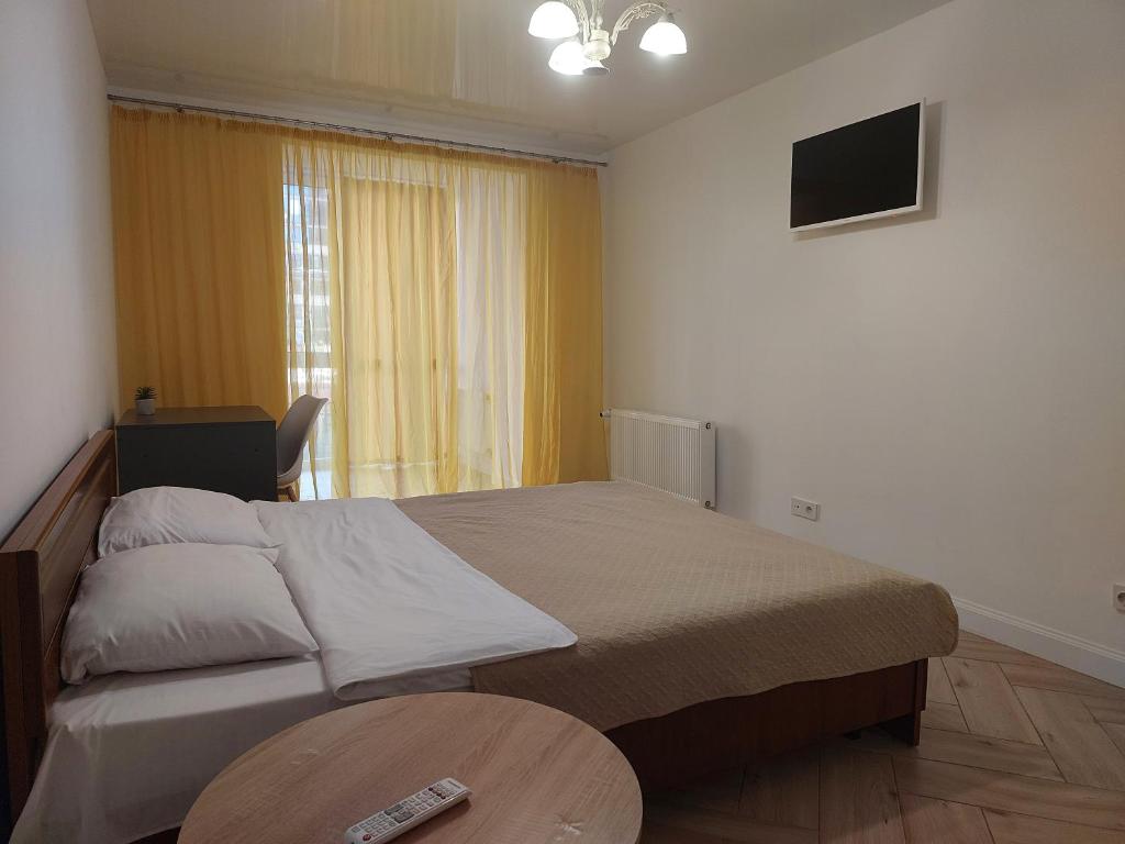 a bedroom with a bed and a table and a television at Апартаменти Класик у ЖК Яровиця in Luts'k