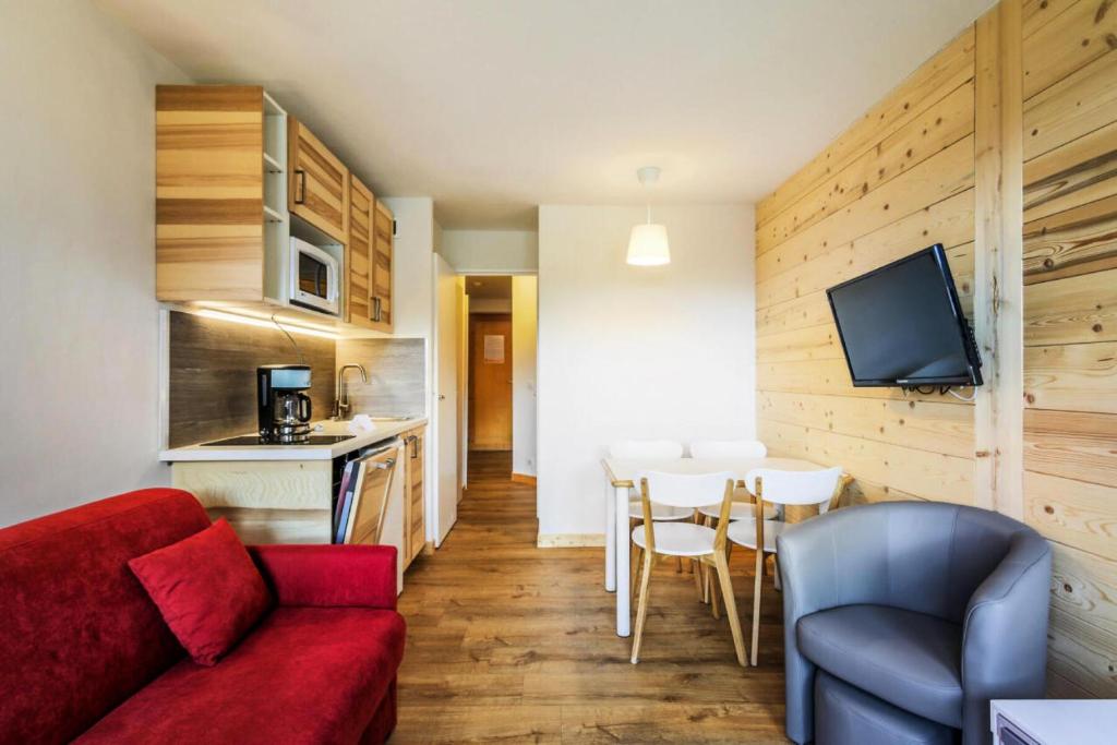 un salon avec un canapé rouge et une table dans l'établissement Résidence Le Hameau du Sauget - maeva Home - 2 Pièces 4 Personnes Sélection MAE-3483, à La Plagne Tarentaise