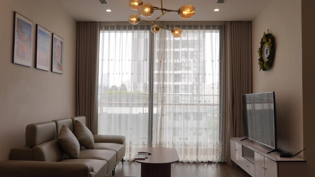 ein Wohnzimmer mit einem Sofa und einem großen Fenster in der Unterkunft Serviced apartment Luxury in Vinhomes Westpoint in Hanoi