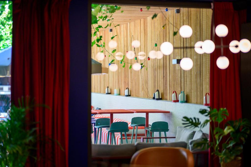 een eetkamer met een tafel, stoelen en verlichting bij ClapClap Hôtel, Food & Bar in Straatsburg