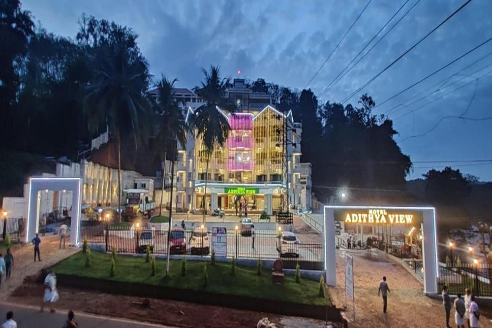 un gran edificio con gente de pie delante de él por la noche en Hotel Adithya View en Dharmastala