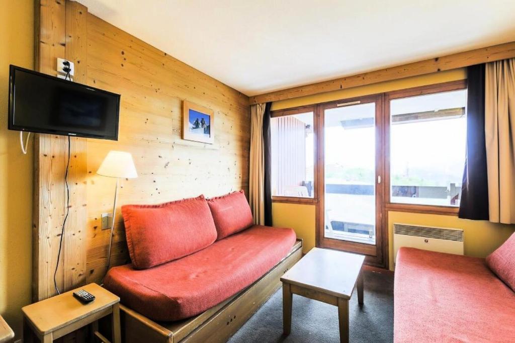 un salon avec un canapé rouge et une télévision dans l'établissement Résidence L'Ours Blanc - maeva Home - Studio 4 personnes - Confort MAE-9906, à Huez