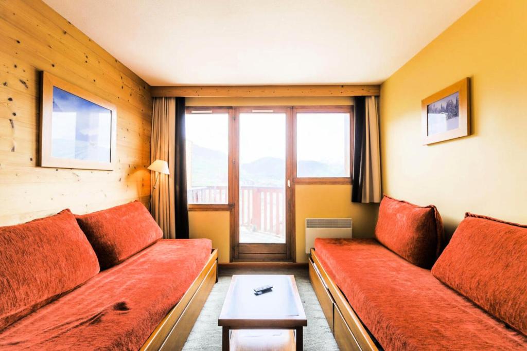 - un salon avec un canapé rouge et une fenêtre dans l'établissement Résidence L'Ours Blanc - maeva Home - Studio 5 personnes Sélection 12, à Huez