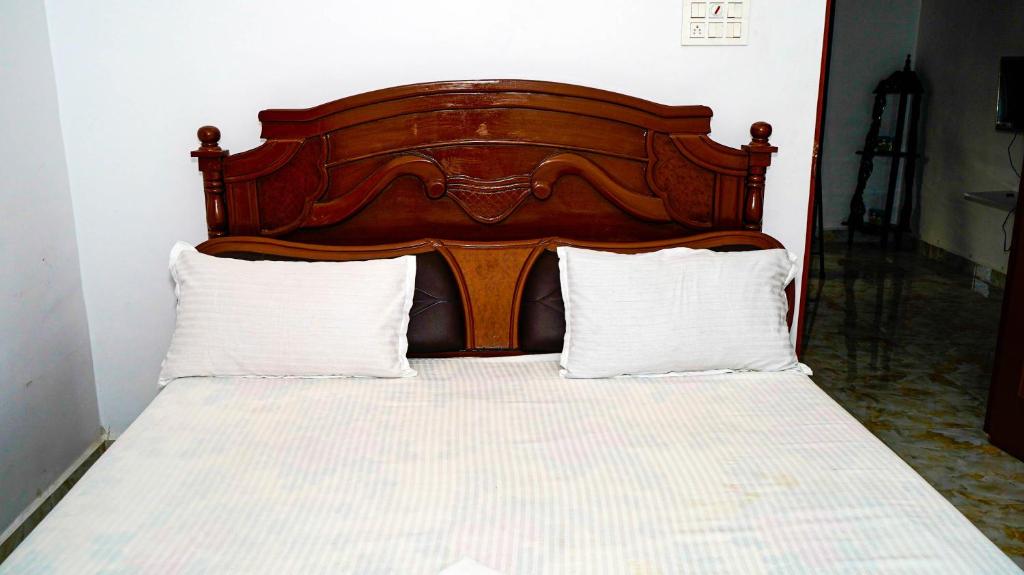 1 cama con cabecero de madera y 2 almohadas blancas en LAGUNA Guesthouse, en Chennai