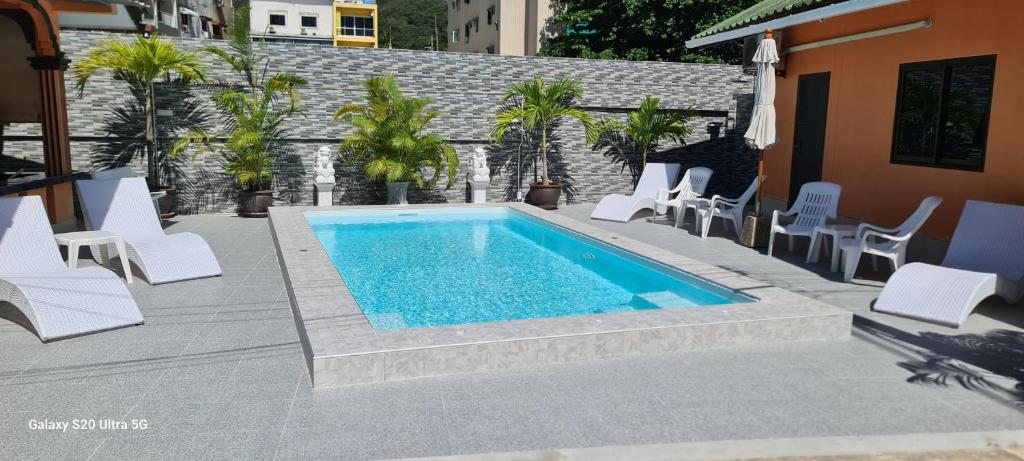 una piscina con tumbonas blancas y un patio en Karon Homes en Karon