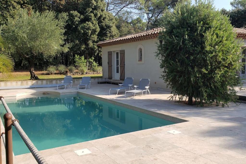 una piscina con sillas y una casa en Charmante Villa Ipsilon, jardin arboré provençal !, en Le Luc