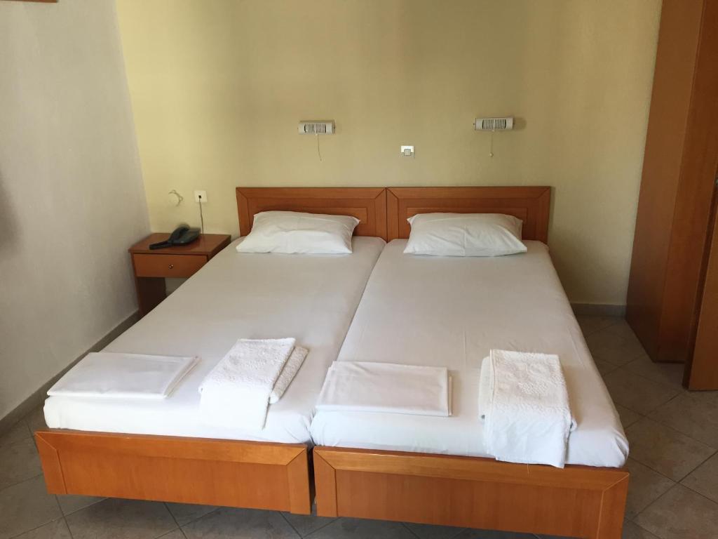 1 dormitorio con 2 camas con sábanas blancas en Iris Hotel, en Nea Kalikratia