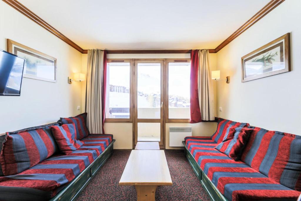 una sala de estar con sofás rojos y azules y una mesa. en Résidence Le Mont Soleil - maeva Home - Appartement 2 Pièces 5 Personnes - 38 en Mâcot La Plagne