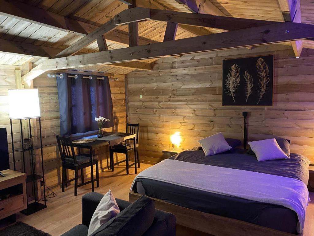 ein Schlafzimmer mit einem Bett und einem Tisch in einem Zimmer in der Unterkunft Bien-être au rendez-vous - Spa Privatif in Blaton