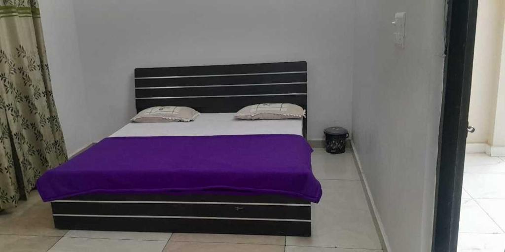 a bedroom with a bed with a purple blanket at OYO Flagship Tirupati Lawn And Hotel in Lucknow