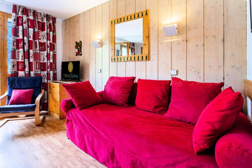 a living room with a red couch and a mirror at Résidence Les Brigues - maeva Home - Appartement 2 Pièces 6 Personnes - Con 98 in Courchevel