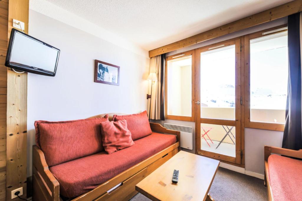 un salon avec un canapé rouge et une table dans l'établissement Résidence Les Constellations - maeva Home - Studio 4 personnes Confort MAE-5086, à La Plagne Tarentaise
