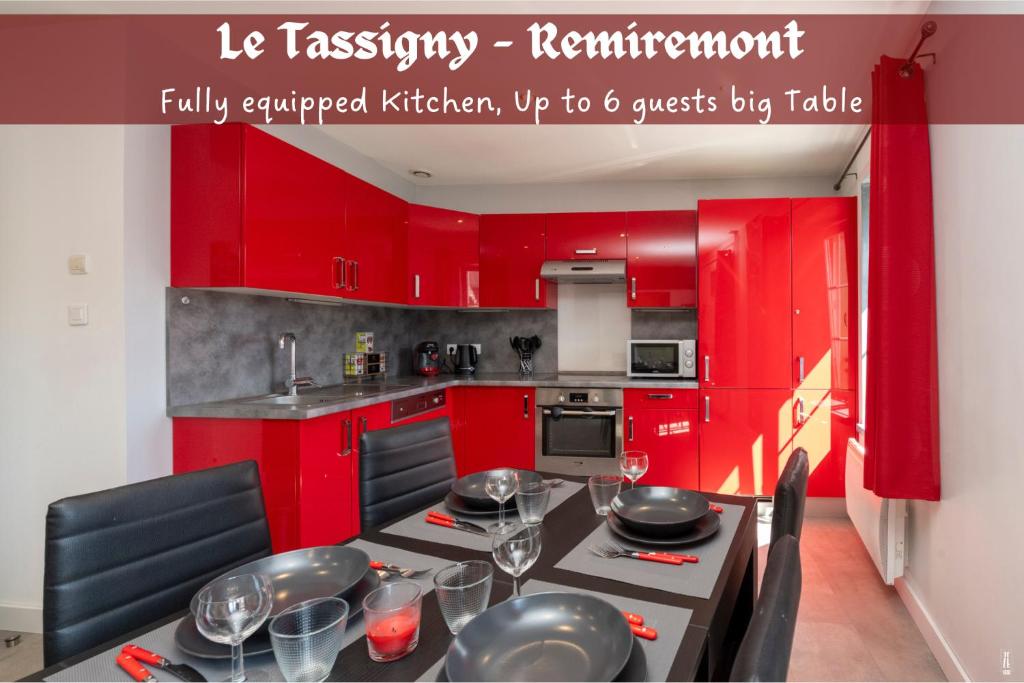 a kitchen with red cabinets and a table with wine glasses at Le Tassigny 3 étoiles - Hyper-Centre Balneo Wifi Parking in Remiremont