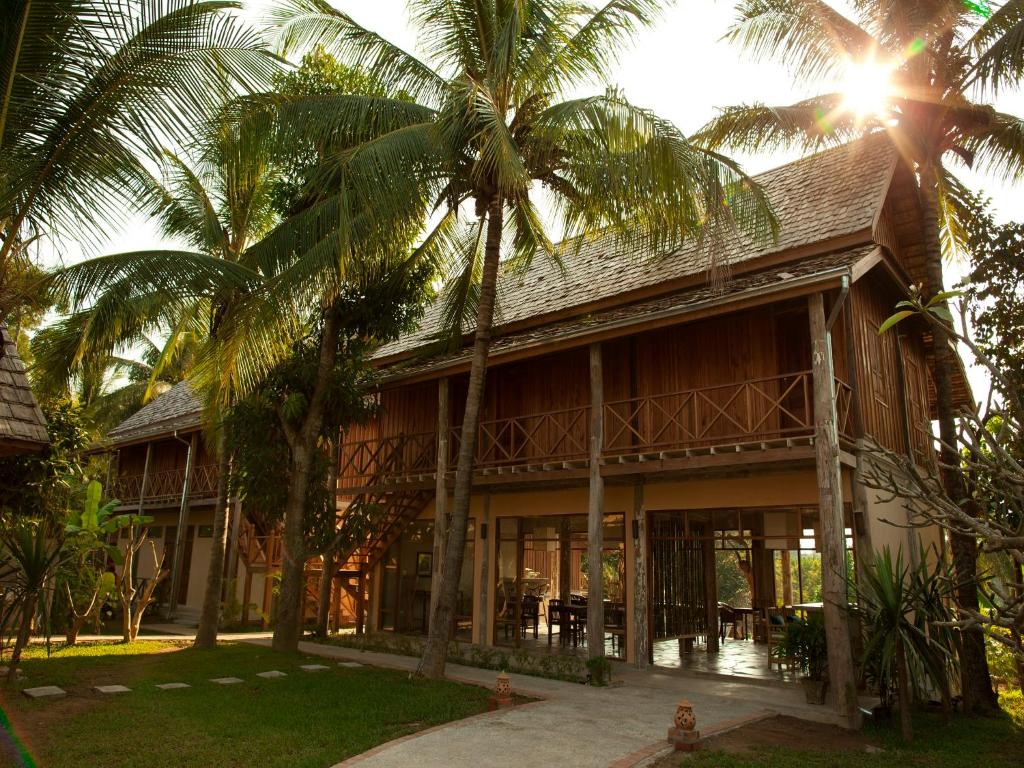 een gebouw met palmbomen ervoor bij My Dream Boutique Resort in Luang Prabang