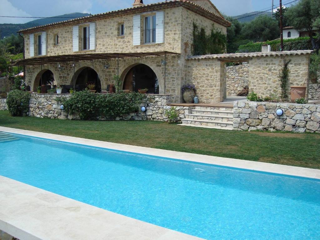 uma casa com piscina em frente a uma casa em Provencal stone farmhouse with sea view, swimming pool and spa em Tourrettes-sur-Loup