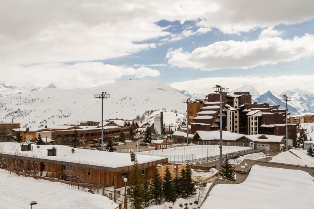 un complexe dans la neige avec des montagnes en arrière-plan dans l'établissement Résidence L'Ours Blanc - maeva Home - Appartement 2 pièces 4 personnes Sélection MAE-5256, à Huez