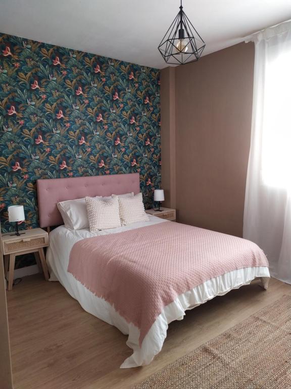 1 dormitorio con cama rosa y papel pintado con motivos florales en DIVINA GUEST HOUSE, en Manzanares