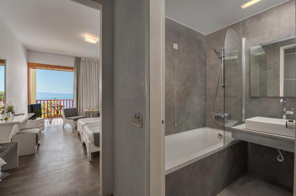 une salle de bain avec une baignoire, un lavabo et une douche dans l'établissement Skiathos Palace Hotel, à Koukounaries