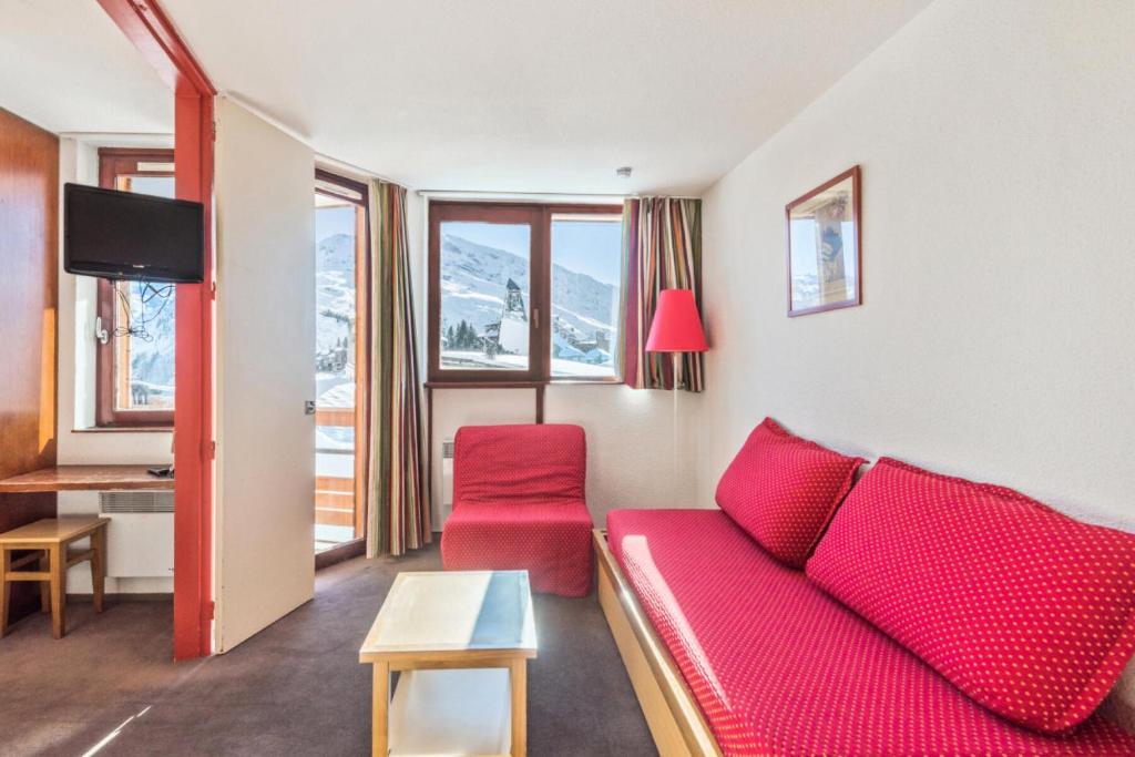 un salon avec un canapé rouge et une table dans l'établissement Résidence Les Fontaines Blanches - maeva Home - Appartement 2 pièces 5 personnes Confort MAE-7288, à Morzine