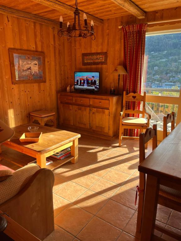 a living room with a television and a table at Appartement cosy, esprit chalet avec jolie vue in Saint-Gervais-les-Bains