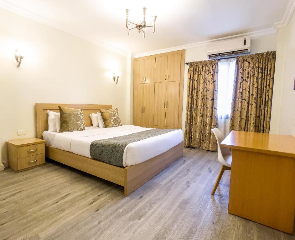 a bedroom with a bed and a desk in it at Maroko Bayshore Suites in Lagos