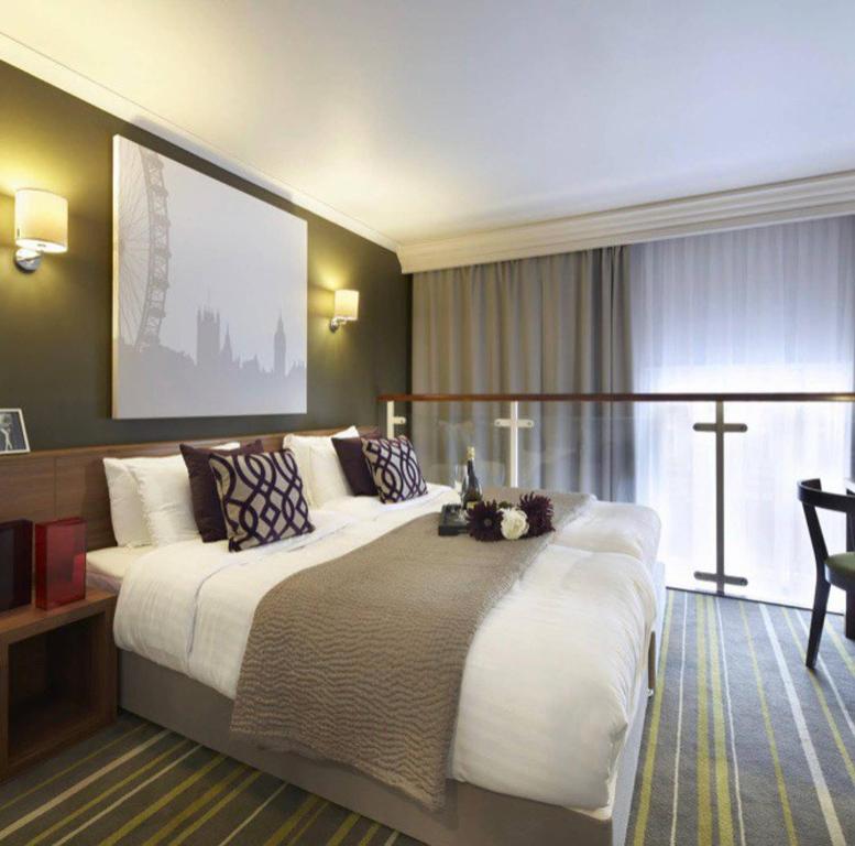 ein großes Bett in einem Hotelzimmer mit einem großen Fenster in der Unterkunft Well Presented Spacious 1 Bed Flat In Kensington in London