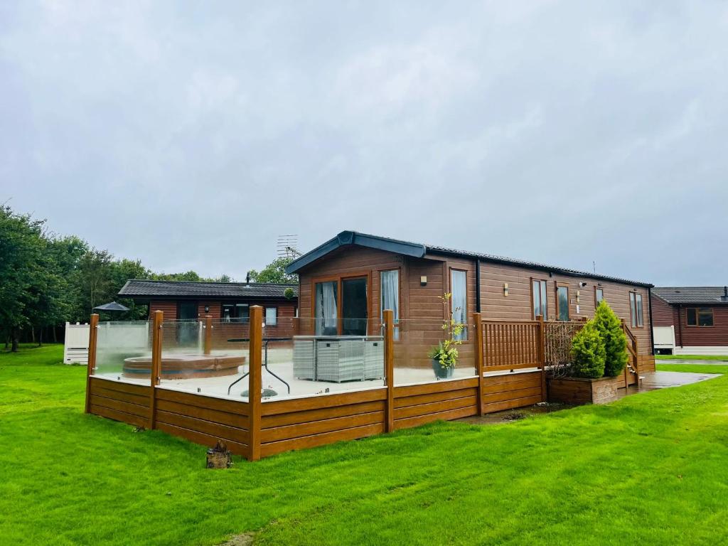 a house with a deck and a yard at Meadows Lodge with Hot Tub in Malton