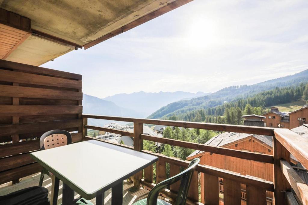 a balcony with a table and chairs and mountains at Résidence Le Hameau des Ecrins - maeva Home - Appartement 2 Pièces 4 Person 62 in Puy-Saint-Vincent