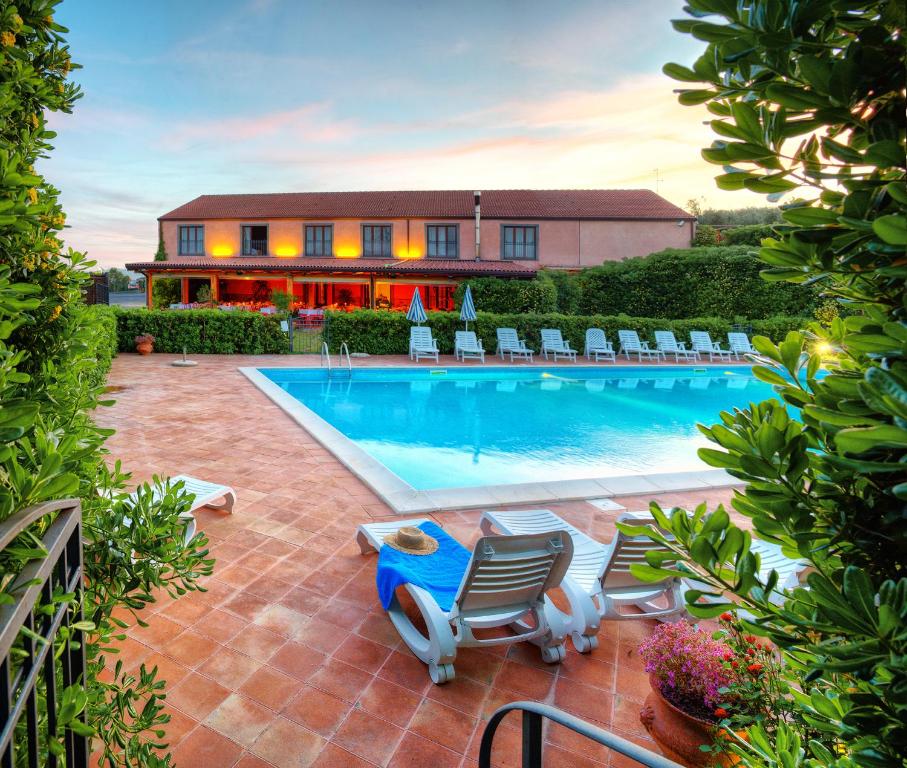 a swimming pool with chairs and a house in the background at Agriturismo Biologico Corte Aragonese in Santa Maria di Licodia