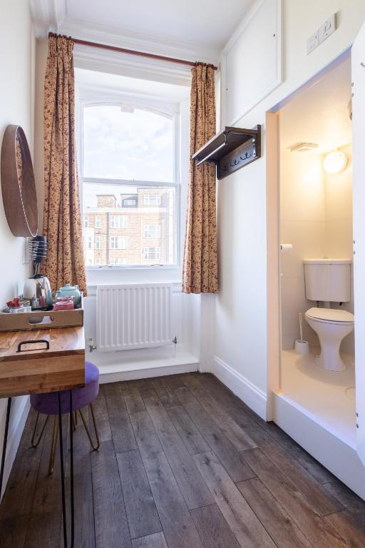 a bathroom with a toilet and a window at Palmers Lodge Swiss Cottage in London