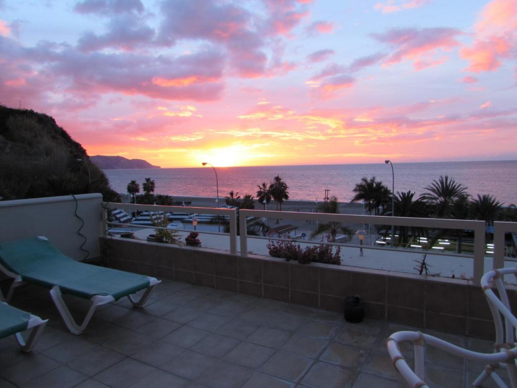 a balcony with a view of the ocean at sunset at Home4Holidays in Nerja