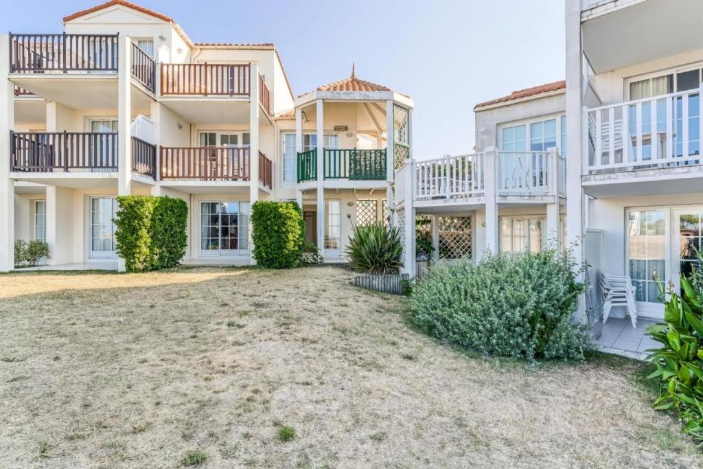 un grand immeuble d'appartements avec balcon et buissons dans l'établissement Résidence Port Bourgenay - maeva Home - Appartement 2 Pièces 6 Personnes - Sélection MAE-5473, à Talmont-Saint-Hilaire