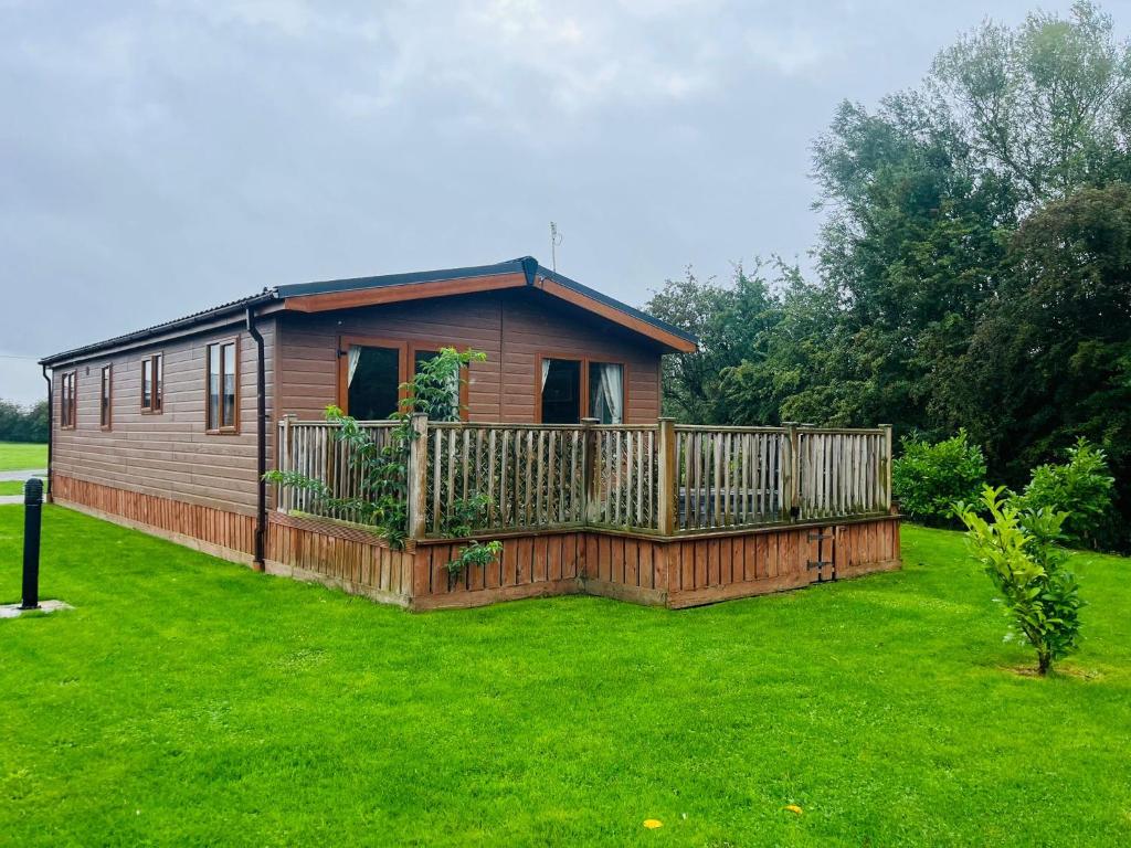a log cabin with a wooden deck in a yard at Springwell Lodge With Hot Tub in Malton