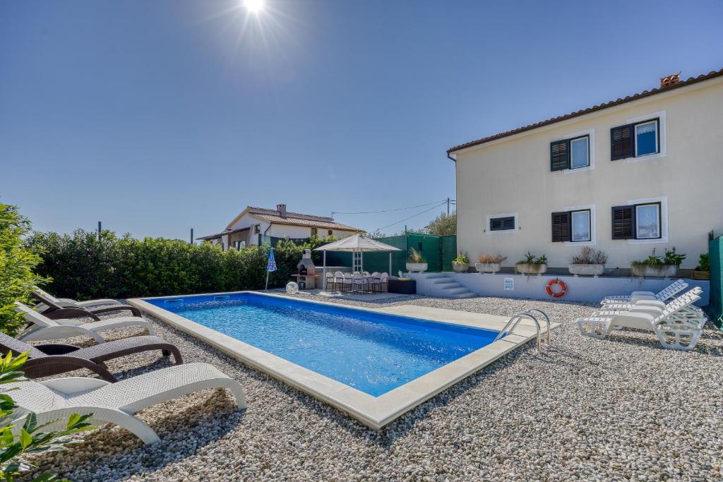 a swimming pool with lounge chairs next to a building at Pool House Lilly - Happy Rentals in Višnjan