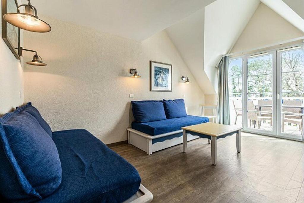 sala de estar con sofá azul y mesa en Résidence Cap Azur - maeva Home - Appartement 3 Pièces 7 Personnes - Confor 52 en Fouesnant
