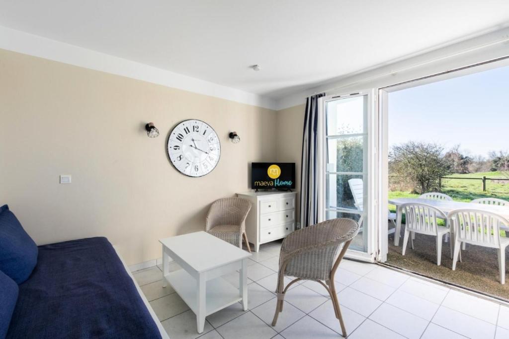 un salon avec un canapé et une horloge au mur dans l'établissement Les Maisons de Port Bourgenay - maeva Home - Maison 3 pièces 6 personnes - Sélection MAE-6631, à Talmont-Saint-Hilaire