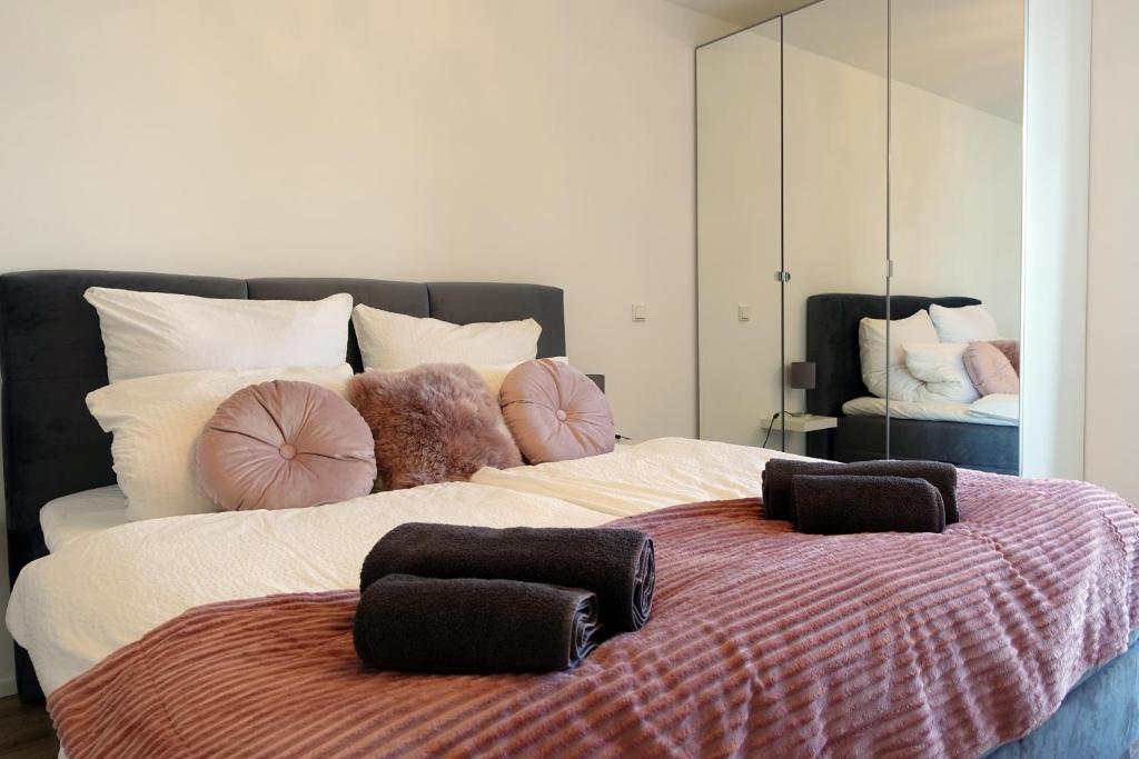 een slaapkamer met een groot bed met kussens erop bij Stilvolles Design Apartment mit Rheinblick inkl Netflix & Parkplatz in Düsseldorf