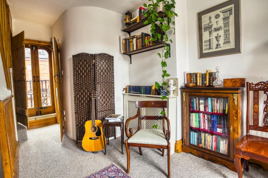 a living room with a guitar and a chair at Pass the Keys Historic House with Cathedral Views in Lincoln