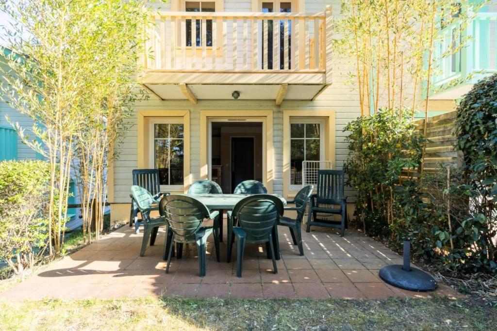 un patio avec une table et des chaises devant une maison dans l'établissement Les Maisons de Lacanau les Pins - maeva Home - Maison 3 pièces 6 personnes - Sélection MAE-7342, à Lacanau