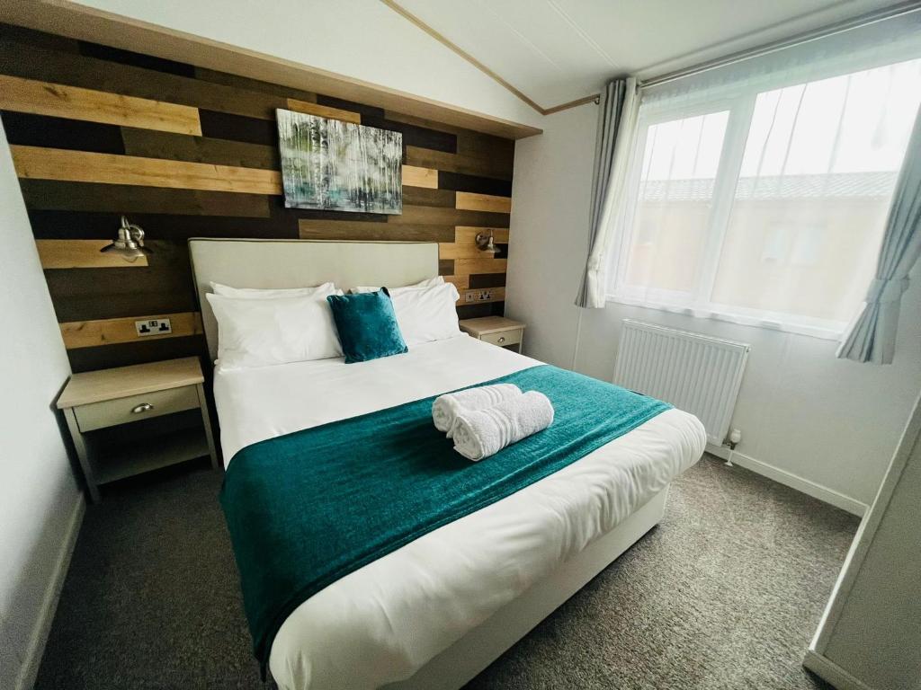 Un dormitorio con una cama grande con una manta azul. en Hedgerow Lodge with Hot Tub, en Malton
