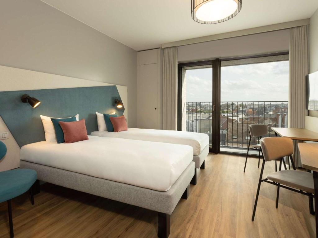 a hotel room with two beds and a large window at Aparthotel Adagio Antwerp City Center in Antwerp