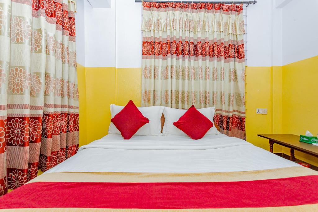 a bedroom with a bed with red and white pillows at OYO 807 Hotel Grand Tokyo in Kathmandu