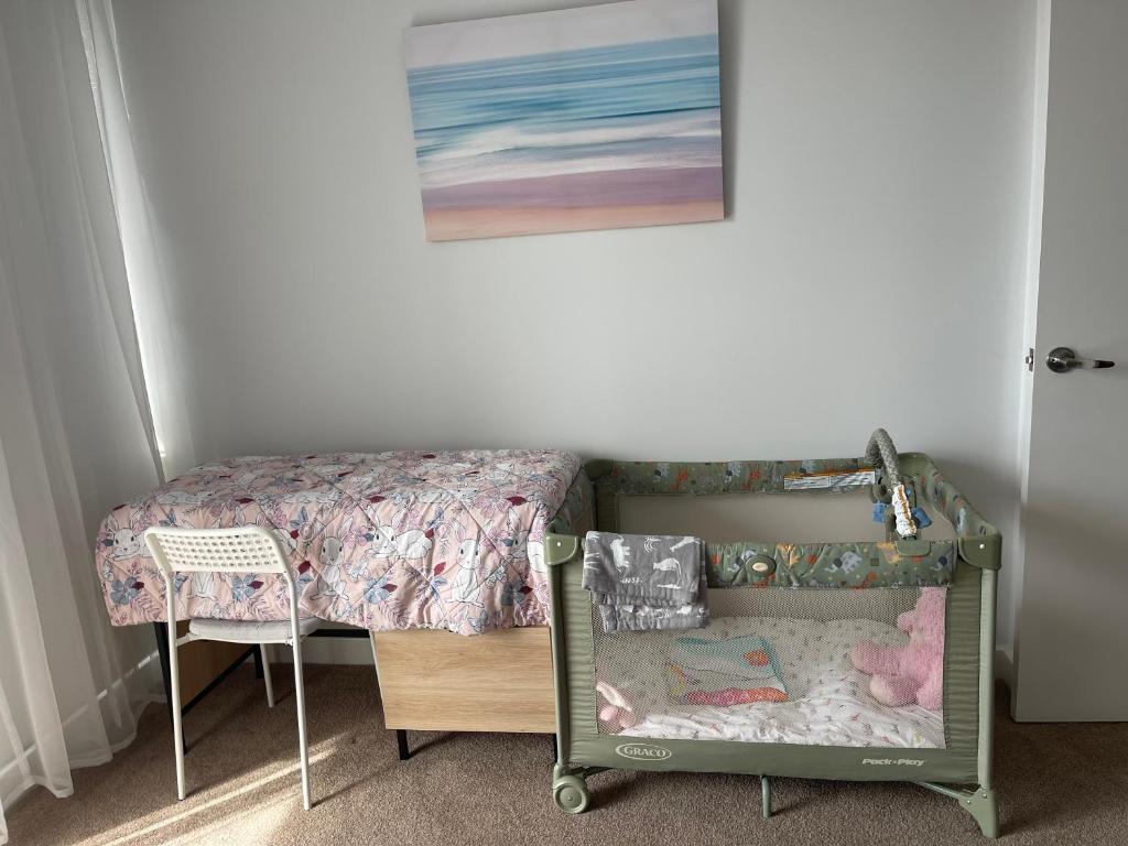a bedroom with a bed and a crib and a chair at Glenelg resort style beachside apartment in Glenelg