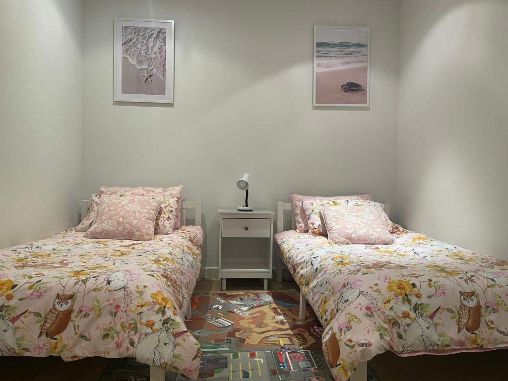 a bedroom with two beds and a table with a night stand at Glenelg resort style beachside apartment in Glenelg