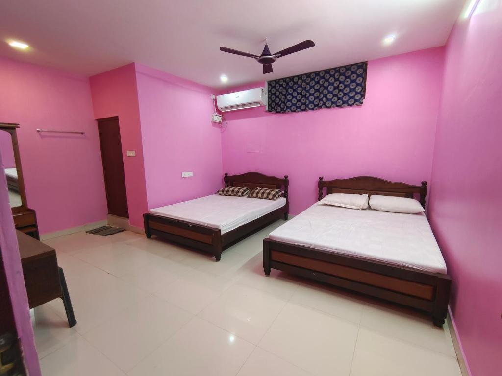 two beds in a room with pink walls at Le Paradise Inn in Puducherry